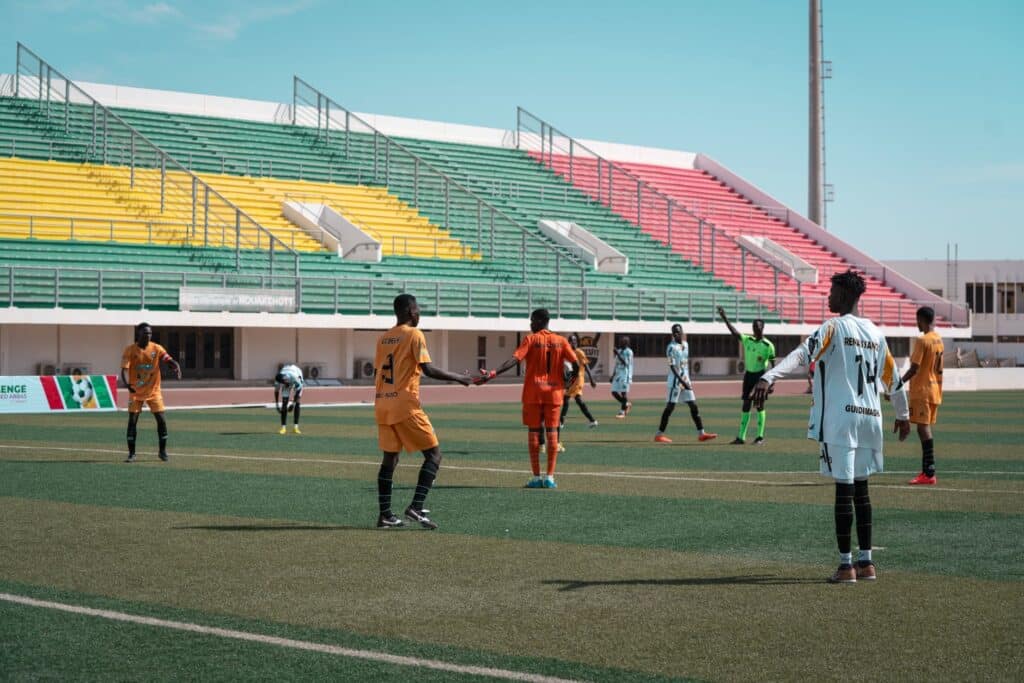 Football players competing for the ball during a match on a stadium pitch