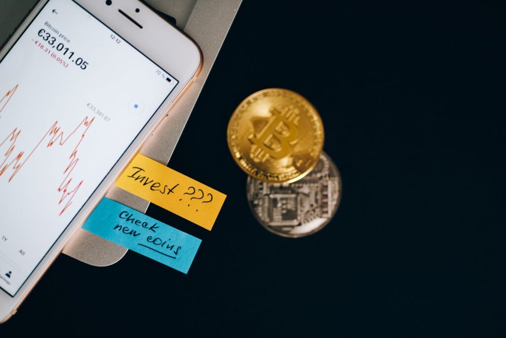 A person holding a smartphone near cryptocurrency coins on a table