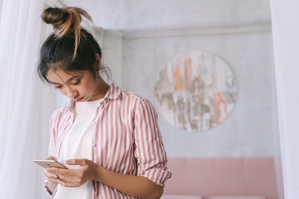 Person sitting on a couch checking a smartphone screen at home