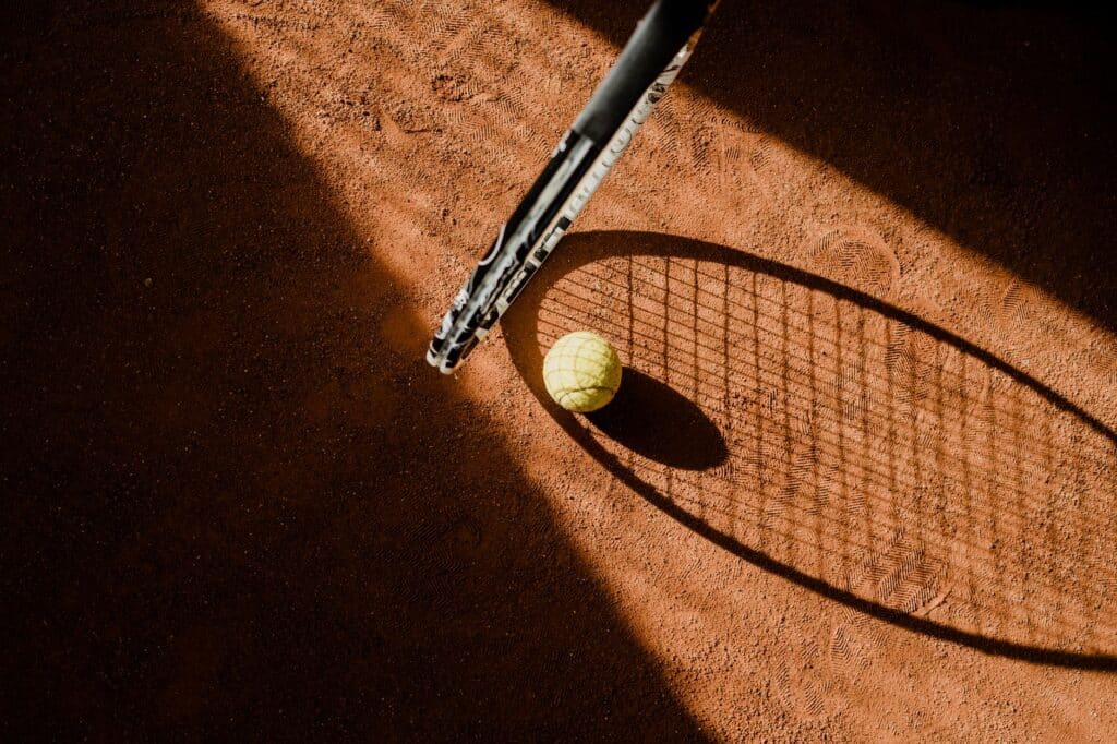 Tennis racket and ball resting on an outdoor court