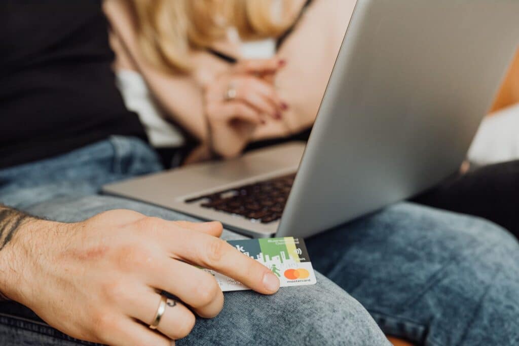 A credit card placed next to a laptop keyboard, suggesting an online payment