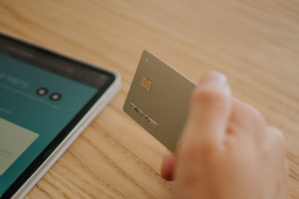 A person holding a credit card while typing on a laptop for an online payment