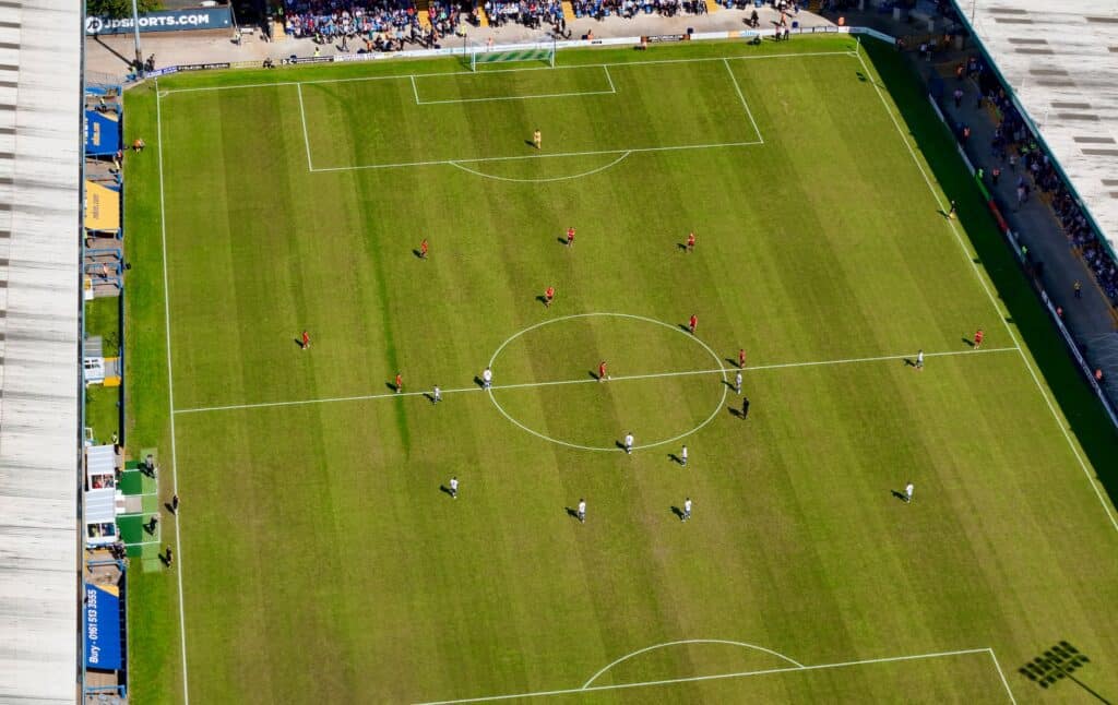 Person holding a smartphone with a sports app open near a stadium