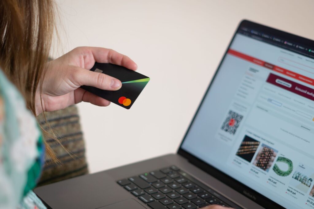Person holding a payment card while using a laptop for an online transaction