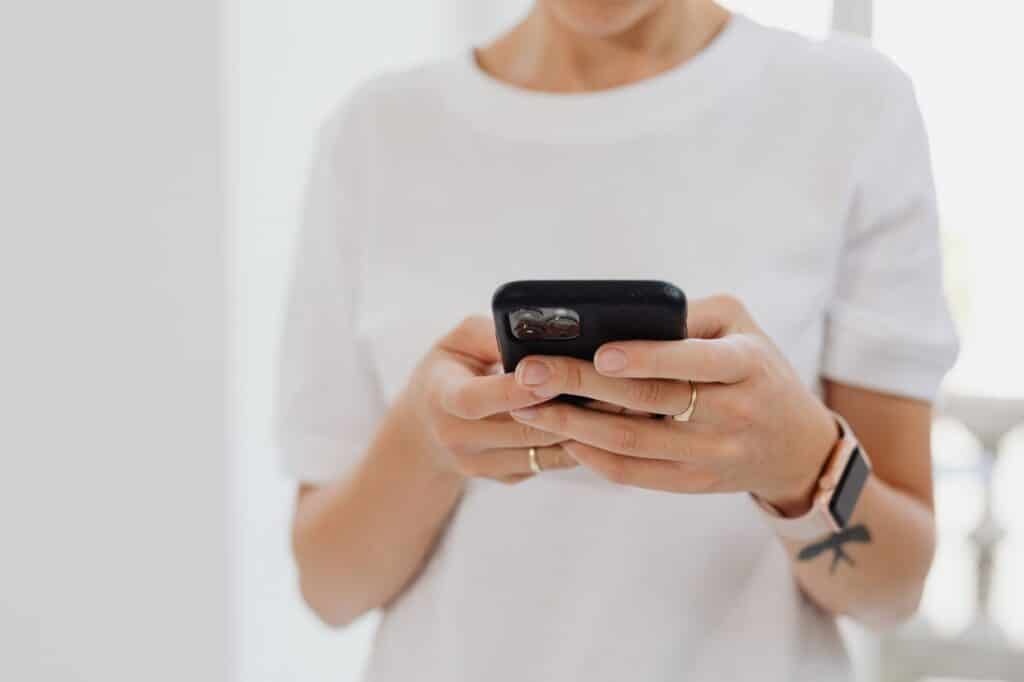 Close-up of hands typing on a smartphone to fill out an online form