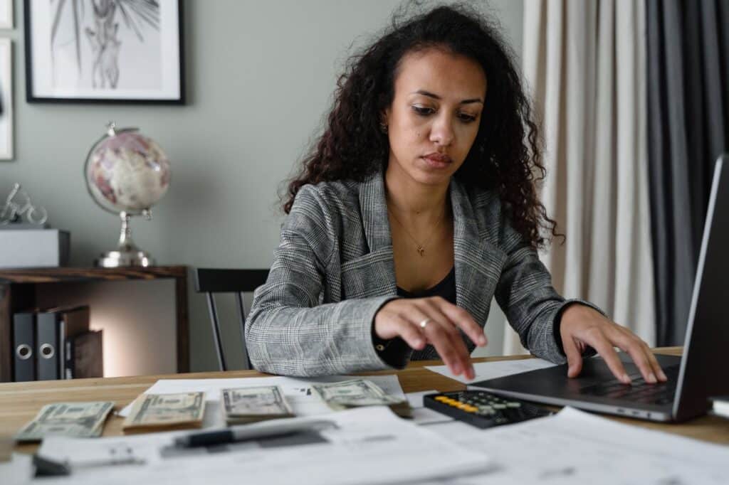 Person reviewing finances on a laptop while taking notes
