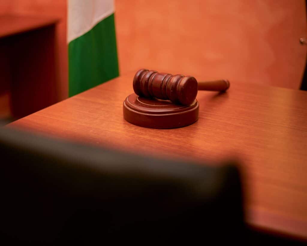 A gavel resting on a wooden desk beside a law book