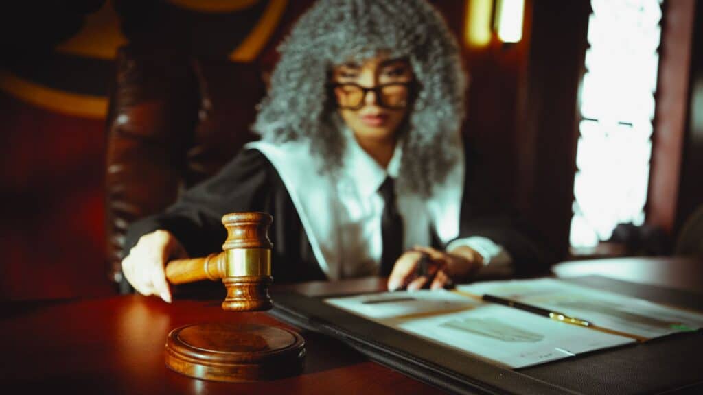 A gavel resting on a wooden desk beside an open law book