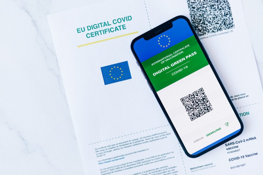 A person holding an ID card beside a laptop during an online verification step.