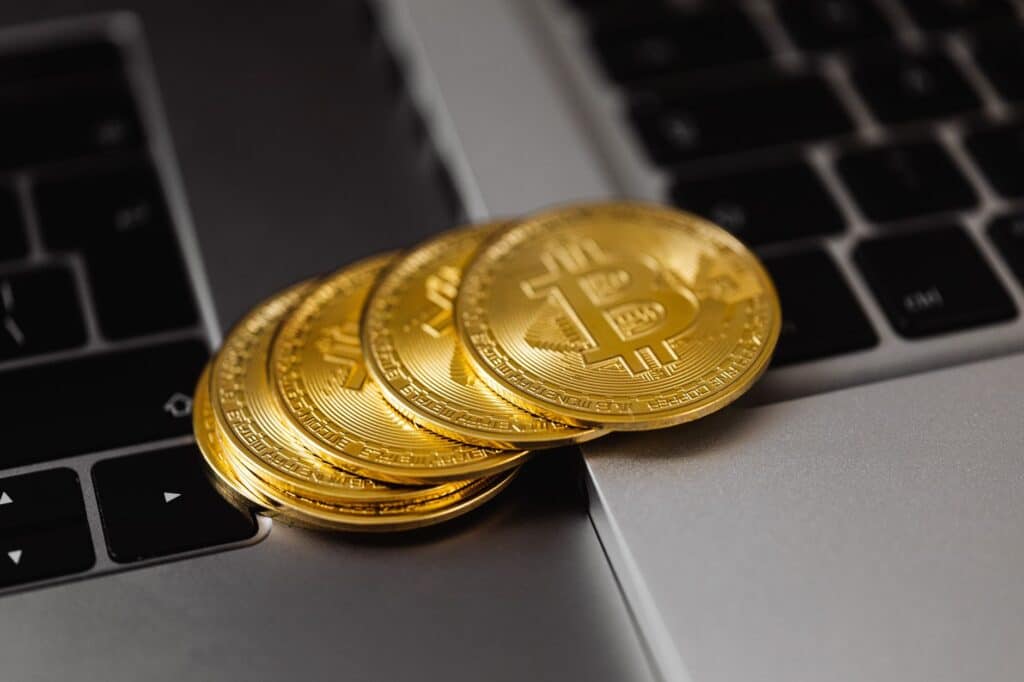Bitcoin coin resting on a laptop keyboard beside a padlock symbol