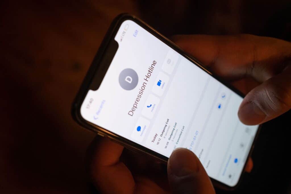 Person holding a phone, sitting quietly as if seeking support or advice