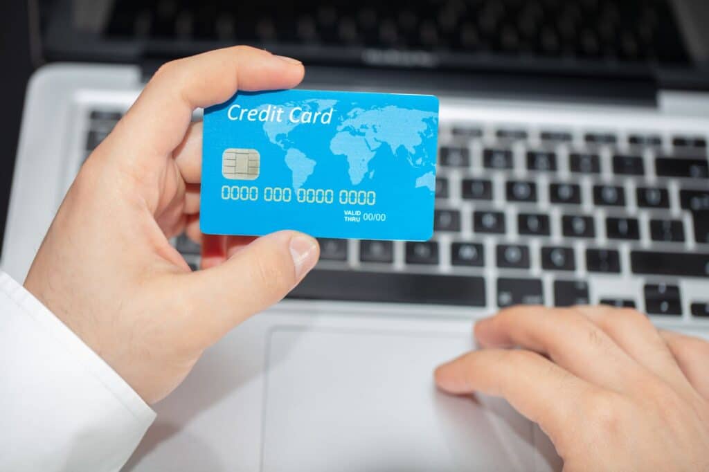 Person using a laptop with a credit card nearby to make an online payment