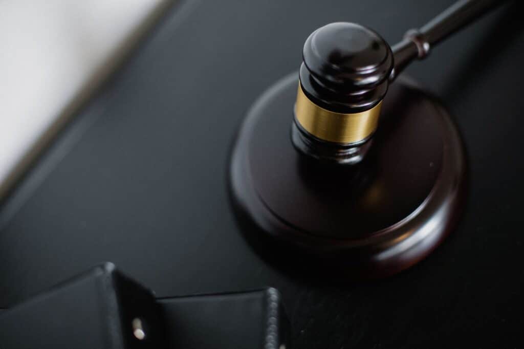 A gavel resting on a wooden desk beside a law book