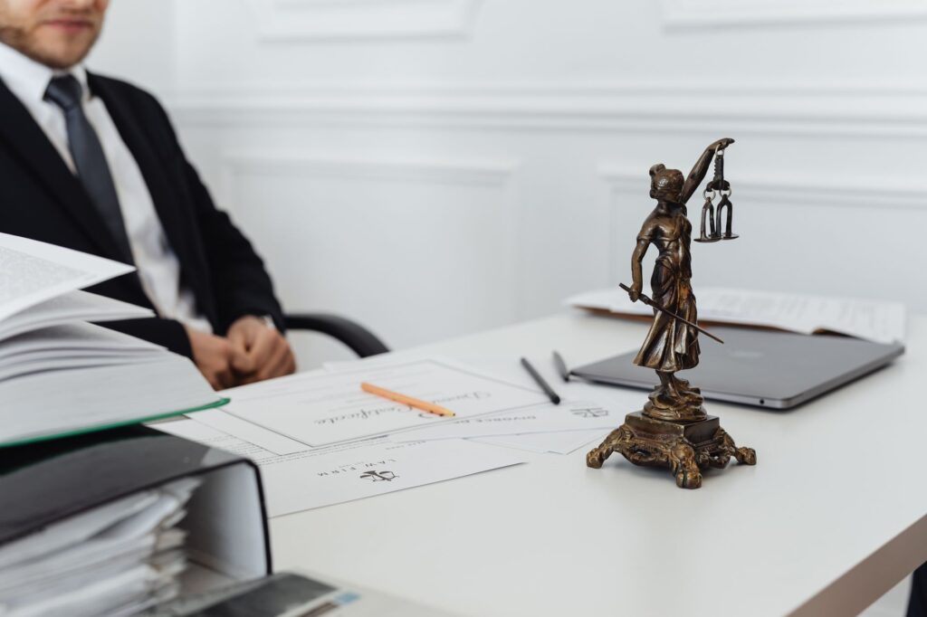 A gavel resting on a wooden desk beside law books