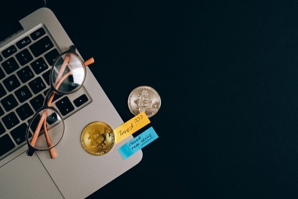 Laptop on a desk with cryptocurrency coins placed beside the keyboard