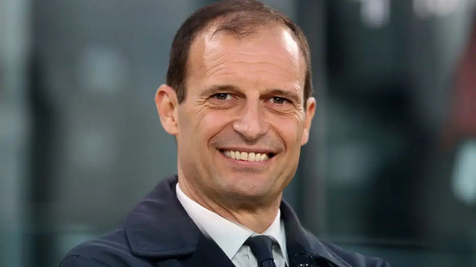 Maximilian Allegri sorrindo em traje formal, provavelmente em uma partida de futebol.