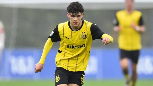 Um jovem jogador de futebol com a camisa amarela do Borussia Dortmund entra em campo.