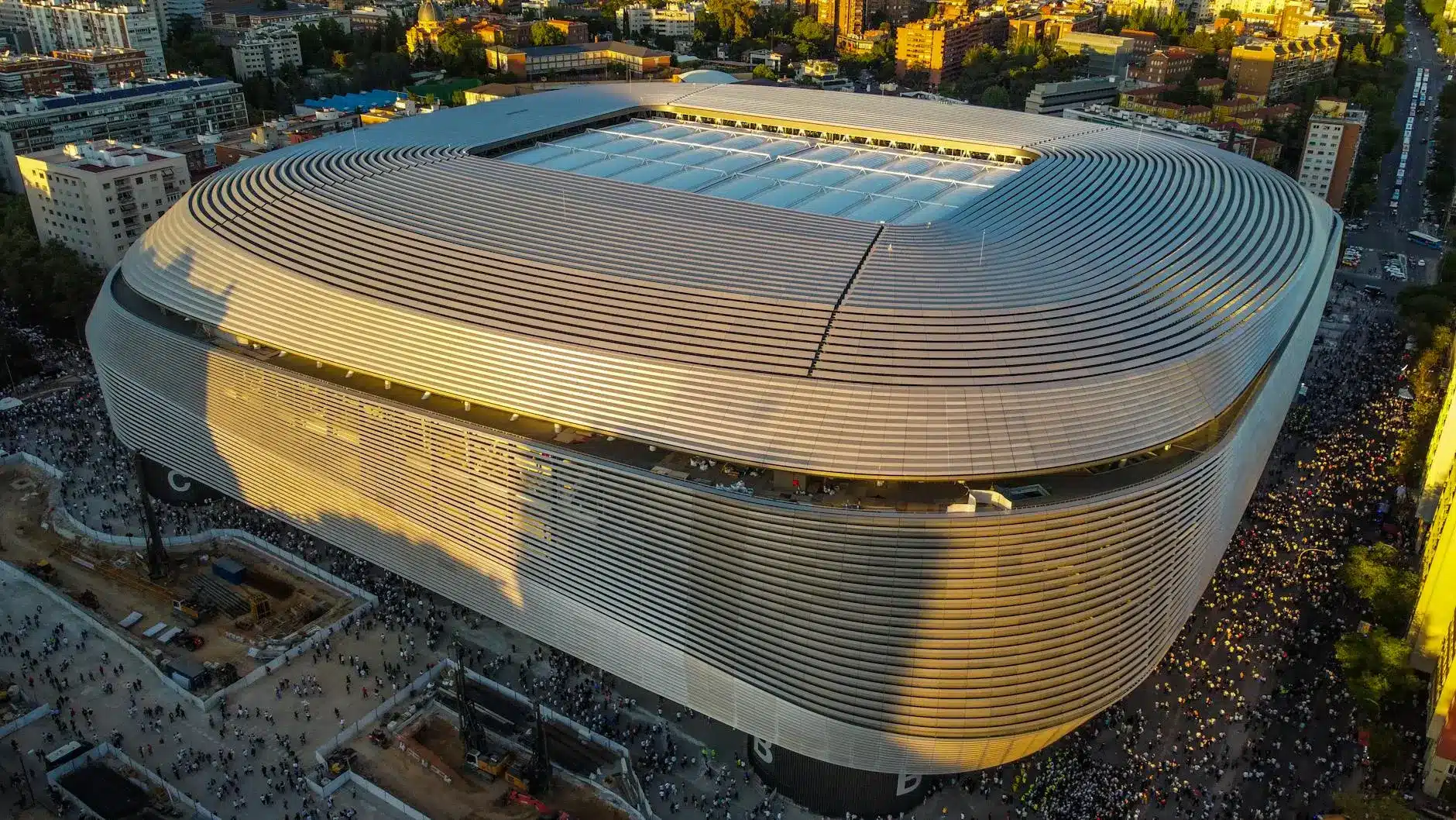 Stadio San Siro di Milano illuminato al tramonto con ambiente urbano.