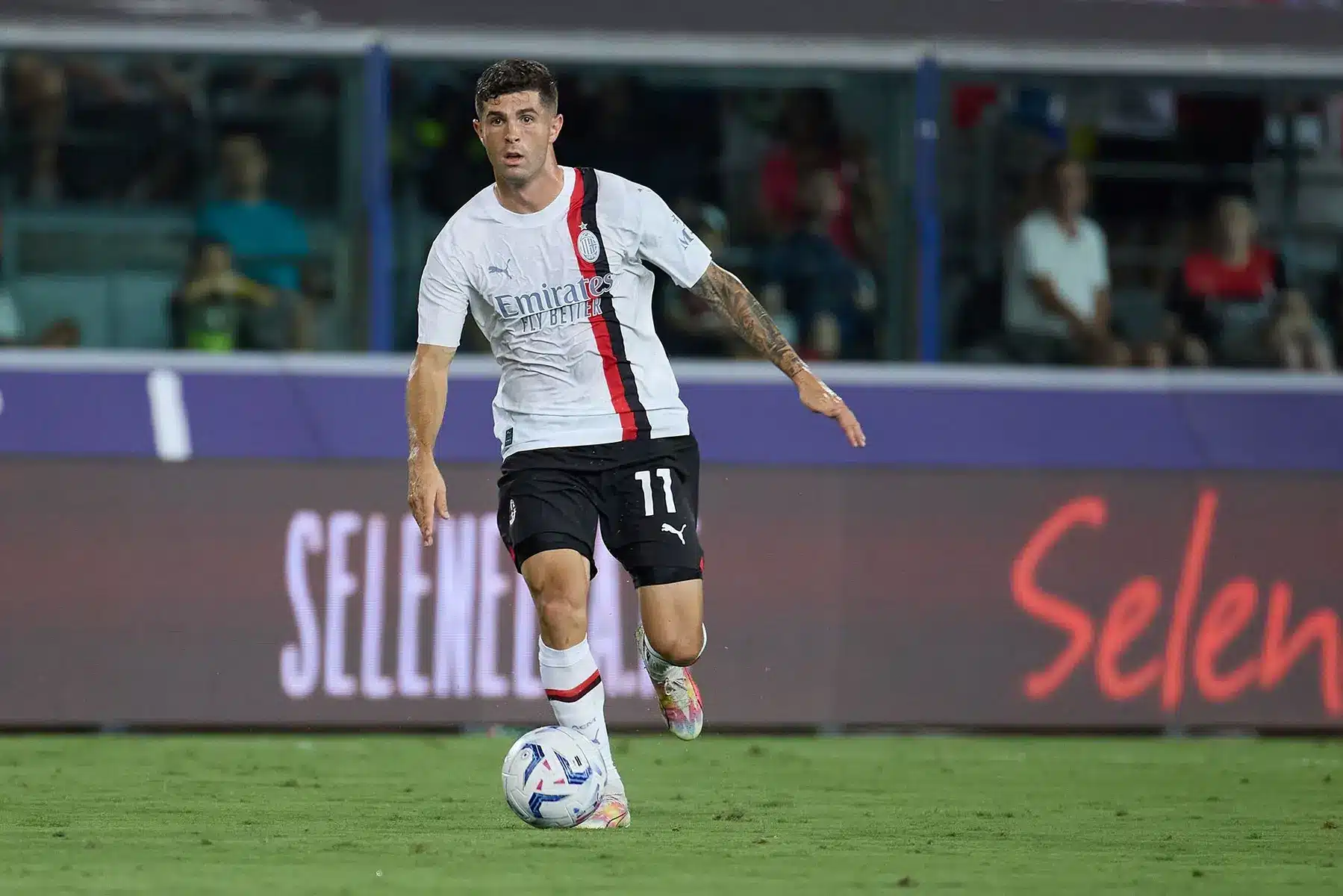 Christian Pulisic dribbling the ball in an AC Milan kit during a match.